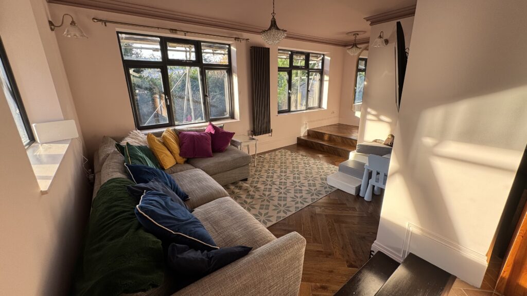 Bright living area within a rear ground floor extension with whole house refurbishment, featuring hardwood flooring and large glass doors.