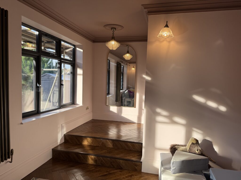 Bright living area within a rear ground floor extension with whole house refurbishment, featuring hardwood flooring and large glass doors.